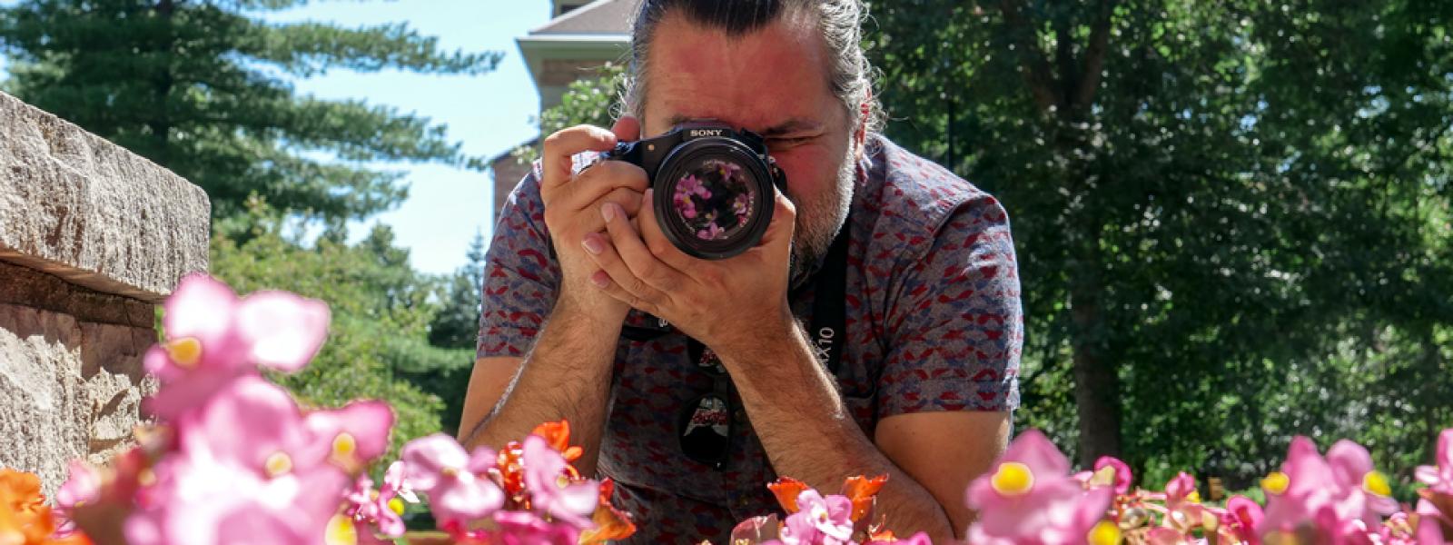 Student using a camera to take a picture of pink flowers.