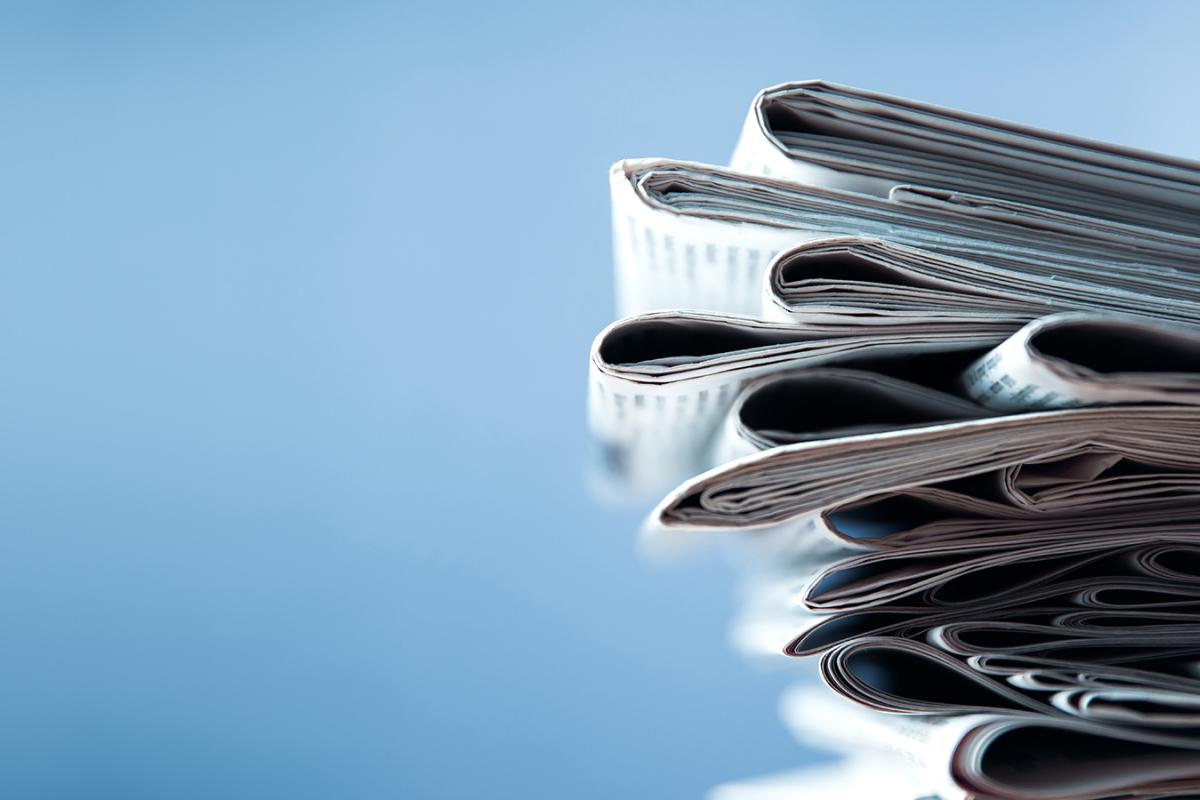 A stack of newspapers against a bright blue background.