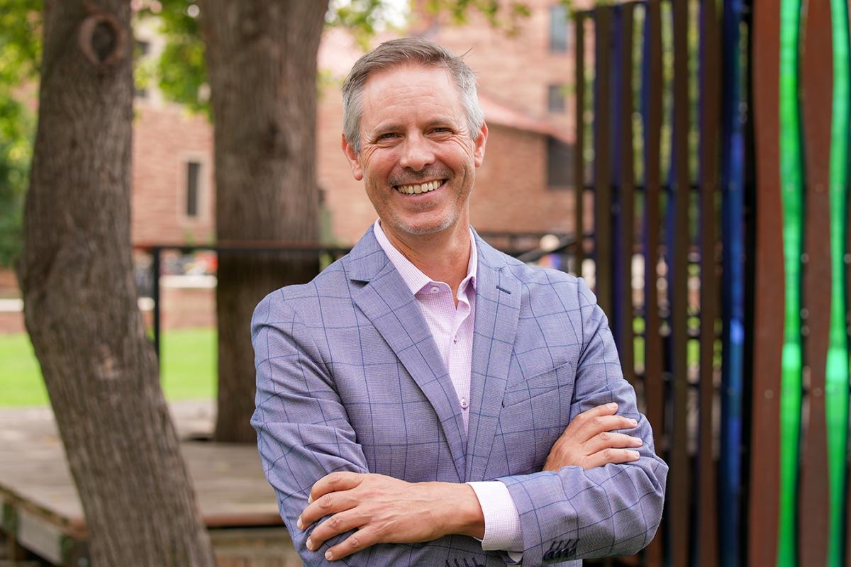 Morgan Young standing in business attire in a natural setting. An outdoor working space is visible in the background.