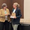 Ashley Carter accepts her best paper award from a woman onstage at the conference.