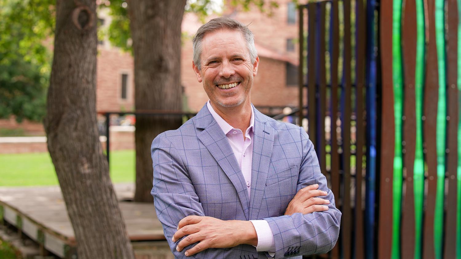 Morgan Young standing in business attire in a natural setting. An outdoor working space is visible in the background.