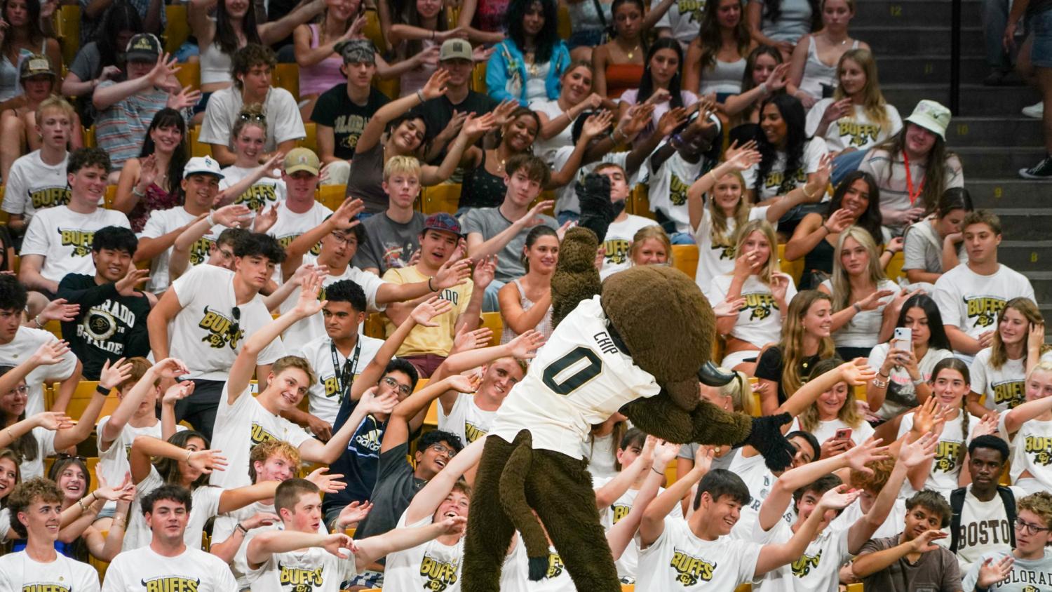 The Buffaloes mascot leads a large group of new students in a basketball arena.