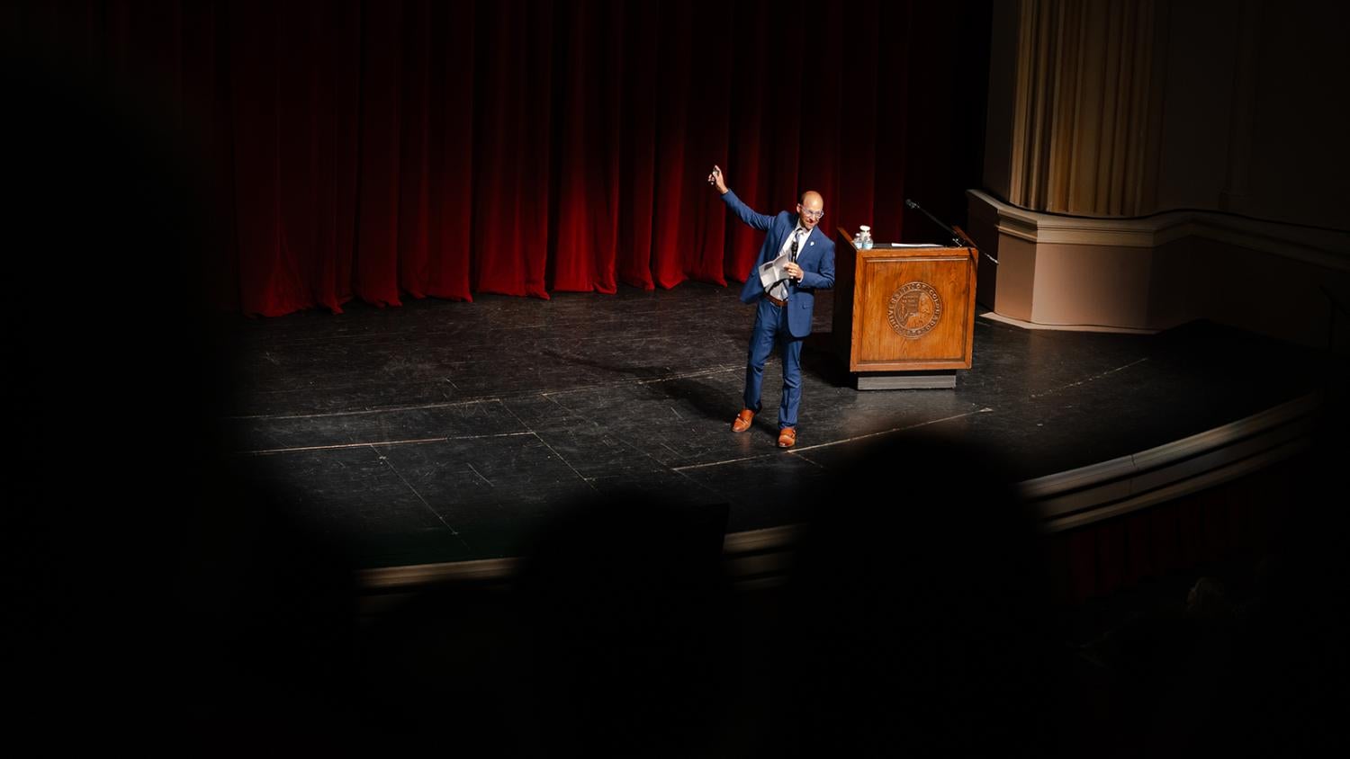 A reporter in business attire gives a lecture onstage in Macky Auditorium.