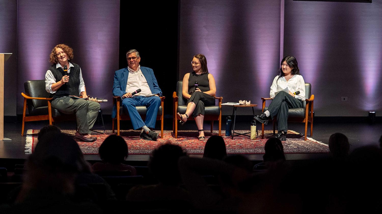 A group of four panelists onstage at a discussion.