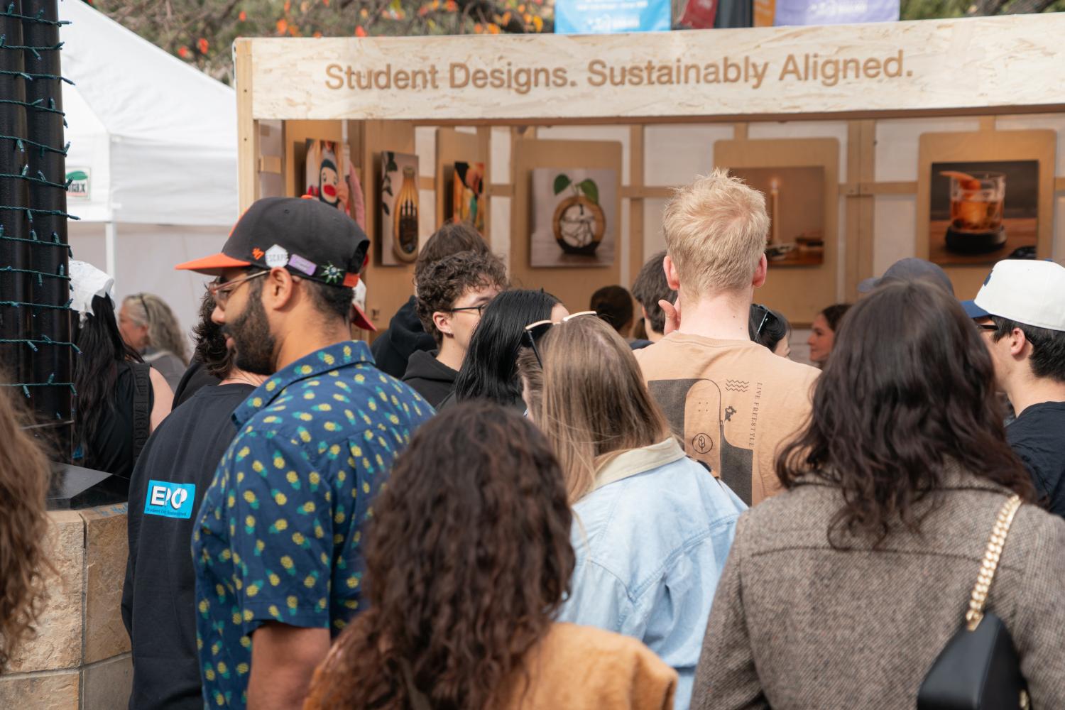 A crowd of people gathered in front of the EPOP shop. Shop reads: "Student Designs. Sustainability Aligned."
