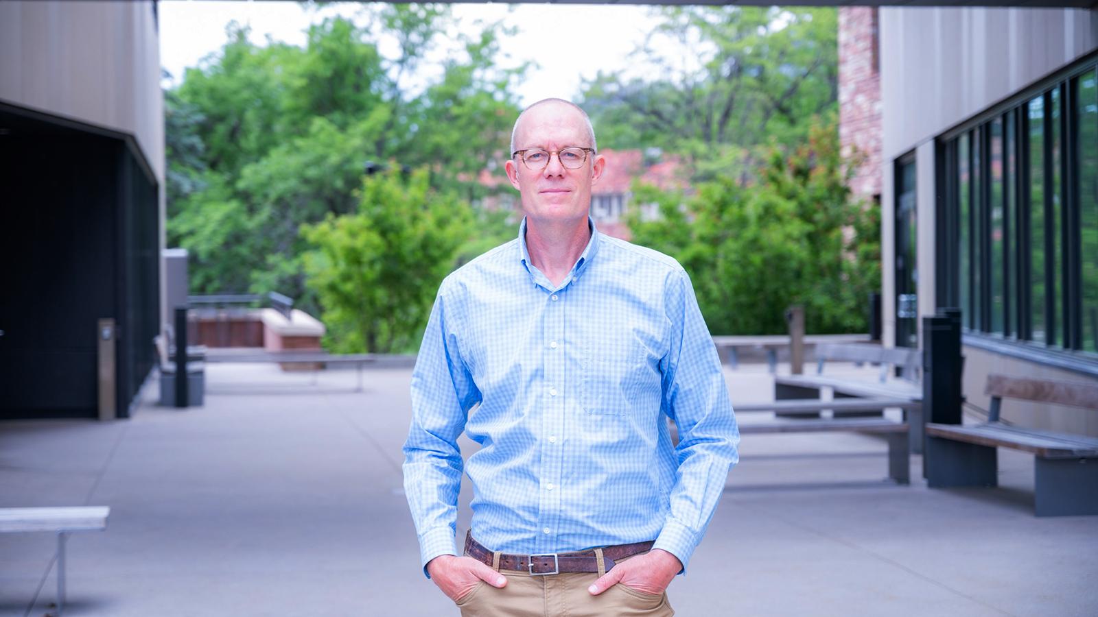 Professor Kevin Hoth stands in an outdoor setting wearing business attire.
