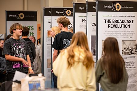 A group of students talking as they examine a museum exhibition.