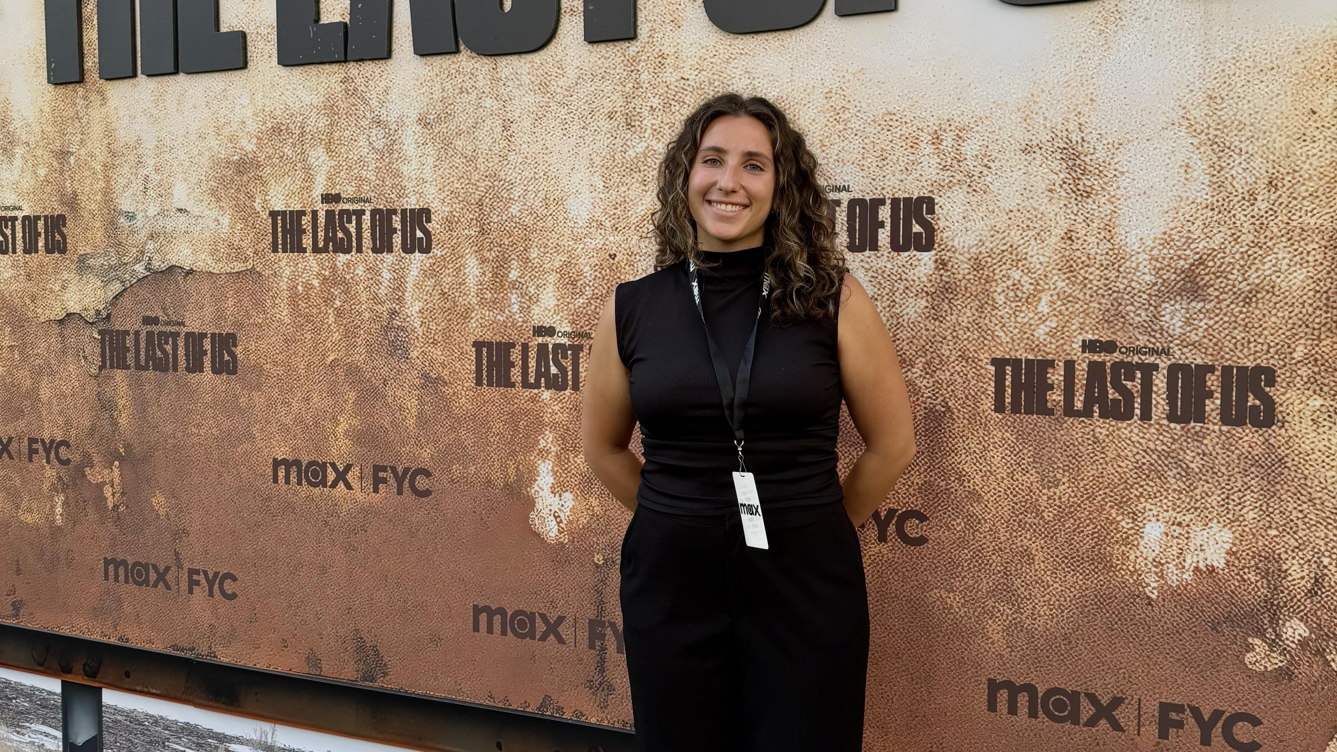 A female student stands in front of a promotional banner for a television show.