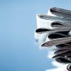A stack of newspapers against a bright blue background.