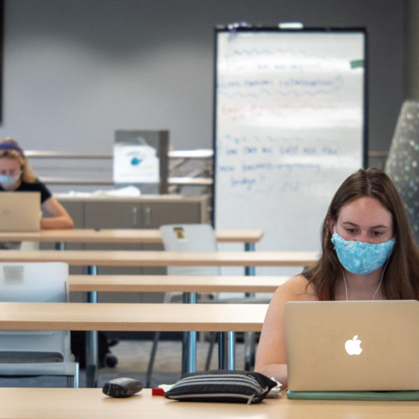 Students do work on computers while socially distanced and wearing masks.