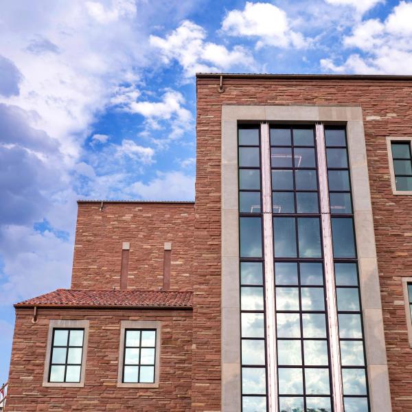 large window of the Imig Music Building against a blue sky