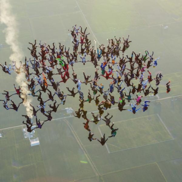 Group of skydivers fall from the sky holding hands
