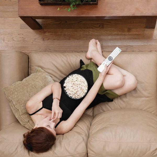 woman on couch eating popcorn holding remote