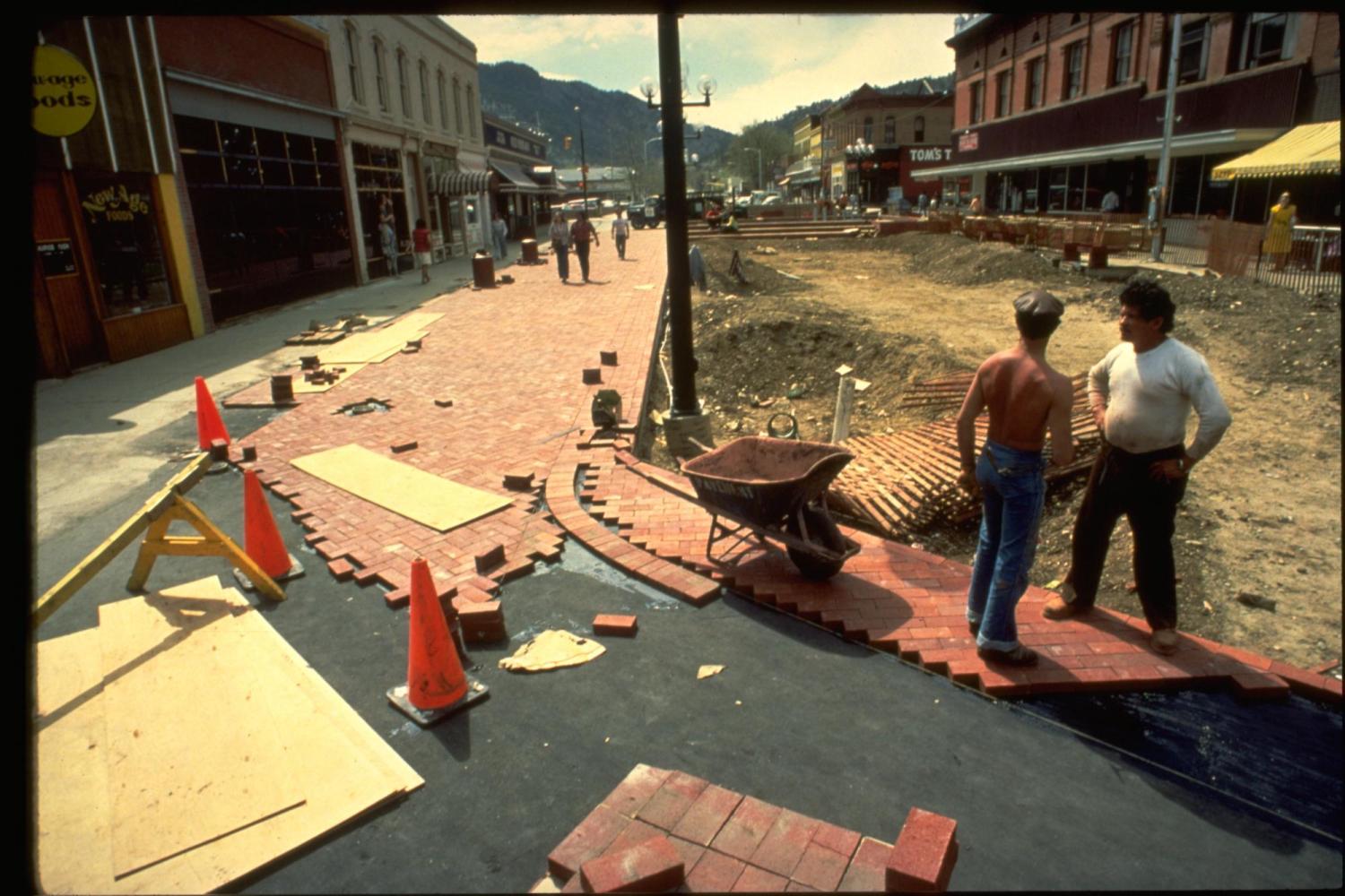 Two men paving Pearl Street with bricks