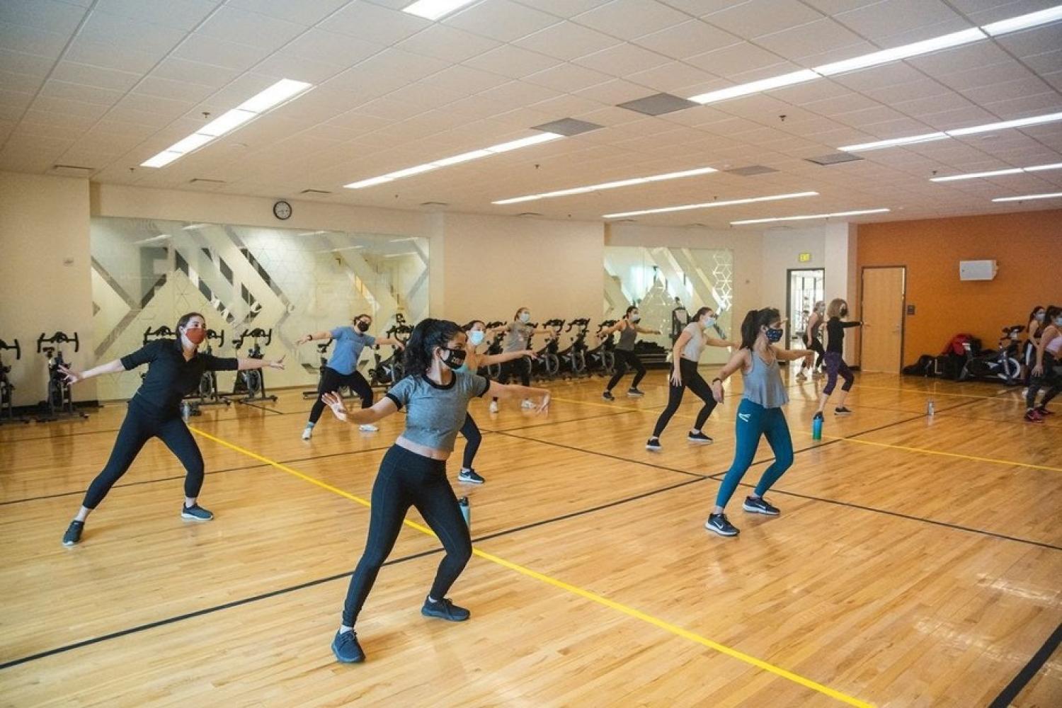A group of socially distanced people wear masks and dance in a gym at the WERQ dance class.