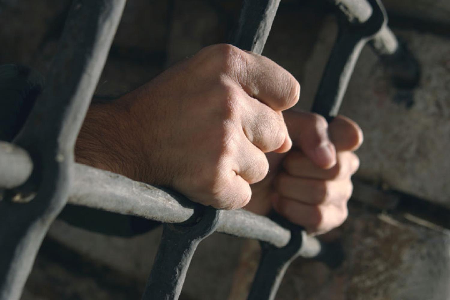 prisoner's hands on bars