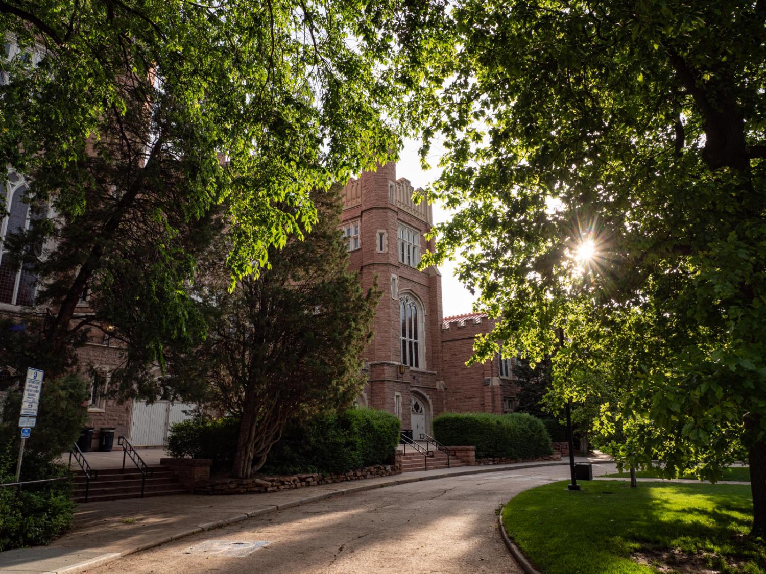 Sunlight peeks through the trees surrounding Macky Auditorium