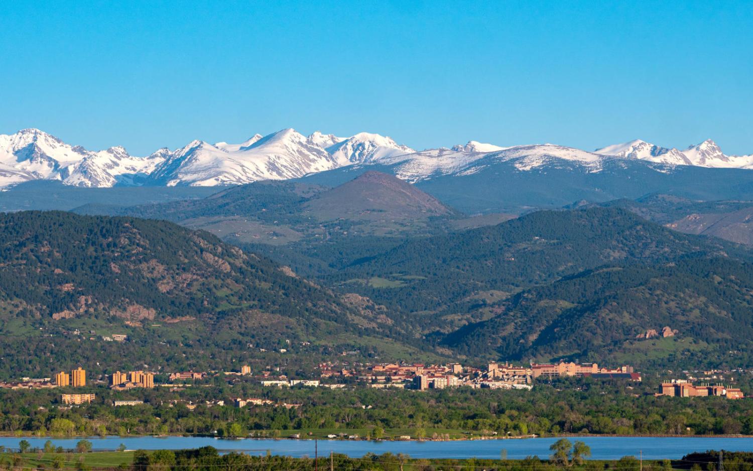 CU's campus stands out against the front range, Rocky mountains, and clear blue sky.