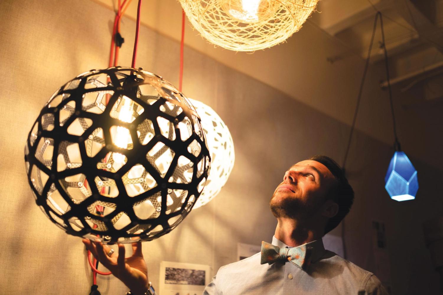 Nicholas Defaria looks at his lamps he created