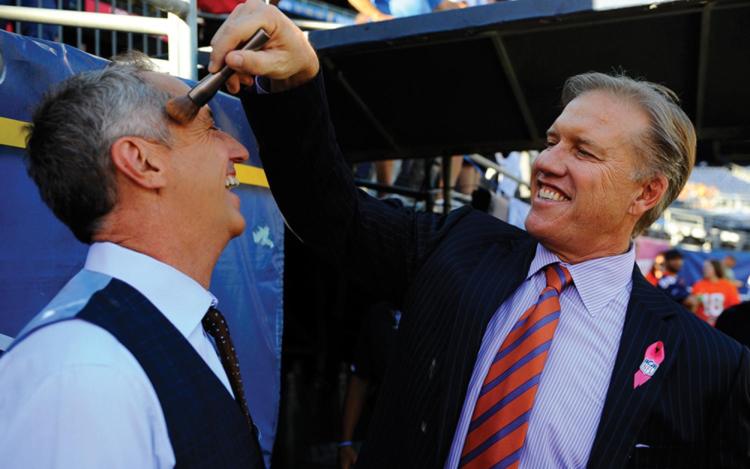 Former Broncos standout John Elway, right, helps Rick Reilly (Jour’81) get ready for Monday Night Football in October 2012.