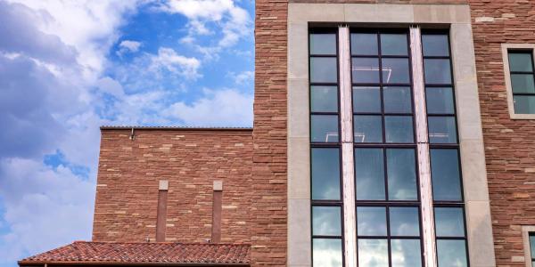 large window of the Imig Music Building against a blue sky