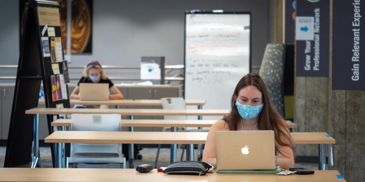 Students do work on computers while socially distanced and wearing masks.