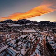A vibrant orange and yellow sunset over the snow covered CU Boulder campus. 