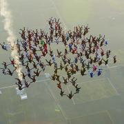 Group of skydivers fall from the sky holding hands