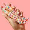 colorfully manicured hand holding two rolls of large smarties candies