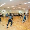 A group of socially distanced people wear masks and dance in a gym at the WERQ dance class. 