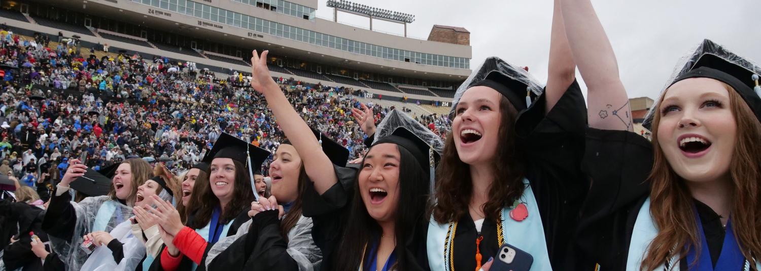 Students celebrating at commencement on Folsom Field