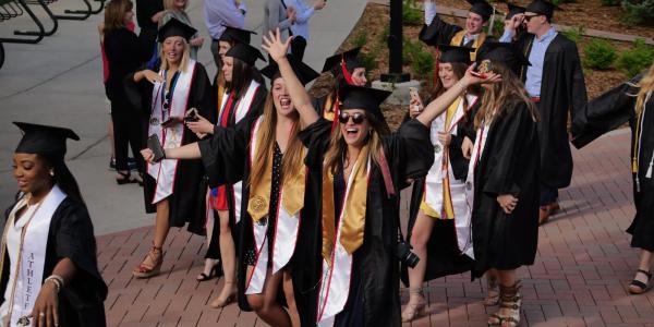 Graduates enjoy the procession from the quad to CU Boulder's 2018 main commencement ceremony at Folsom Field