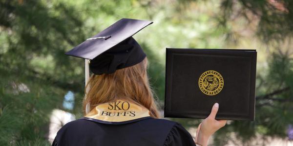 A graduate with a Sko Buffs stole and their diploma cover