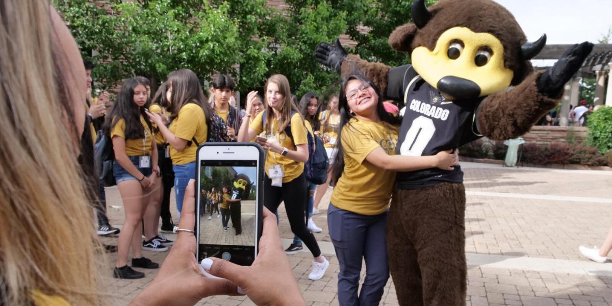 Student taking a picture of Chip the Buffalo with phone