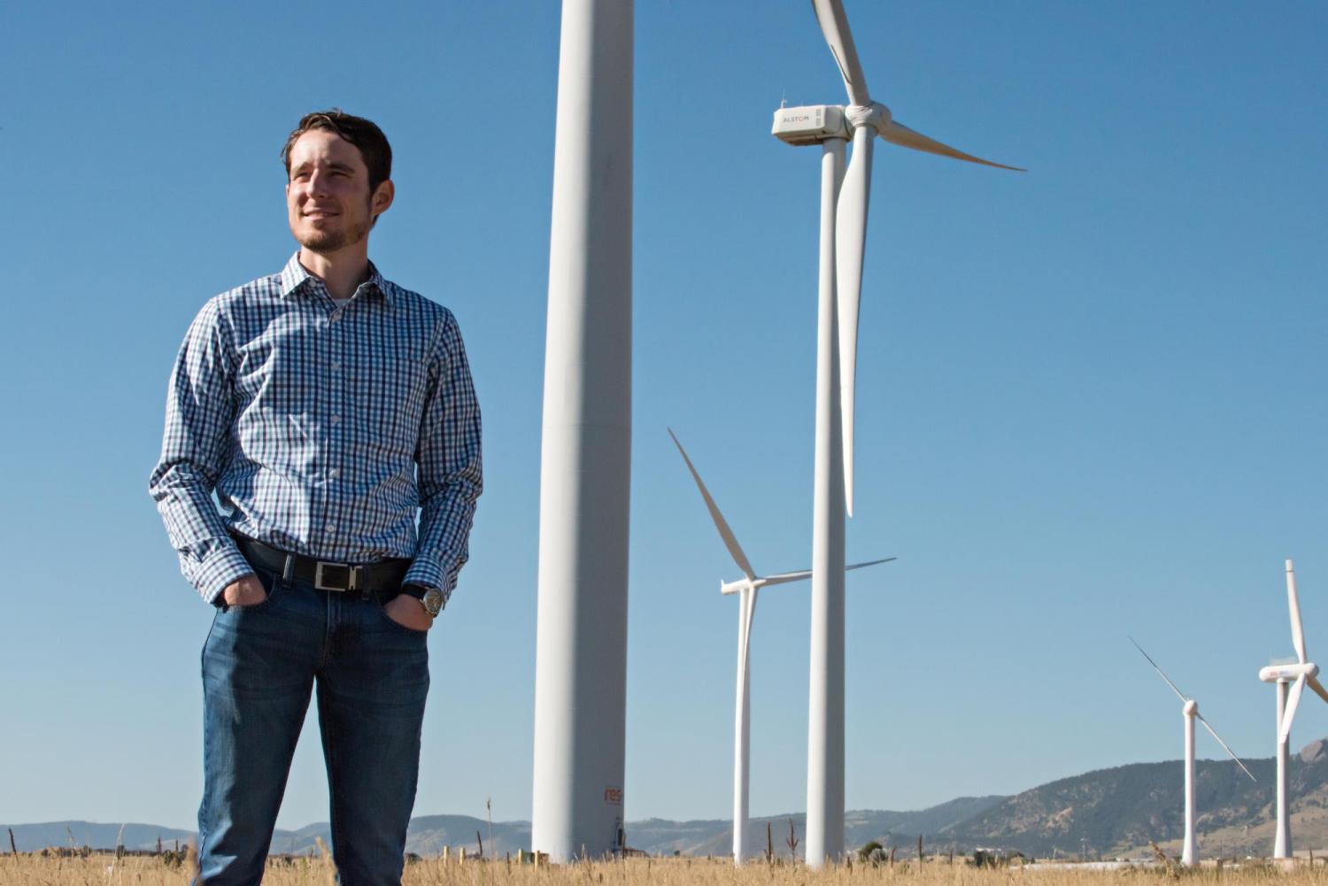 Eric Lantz standing in a field in front of wind turbines.