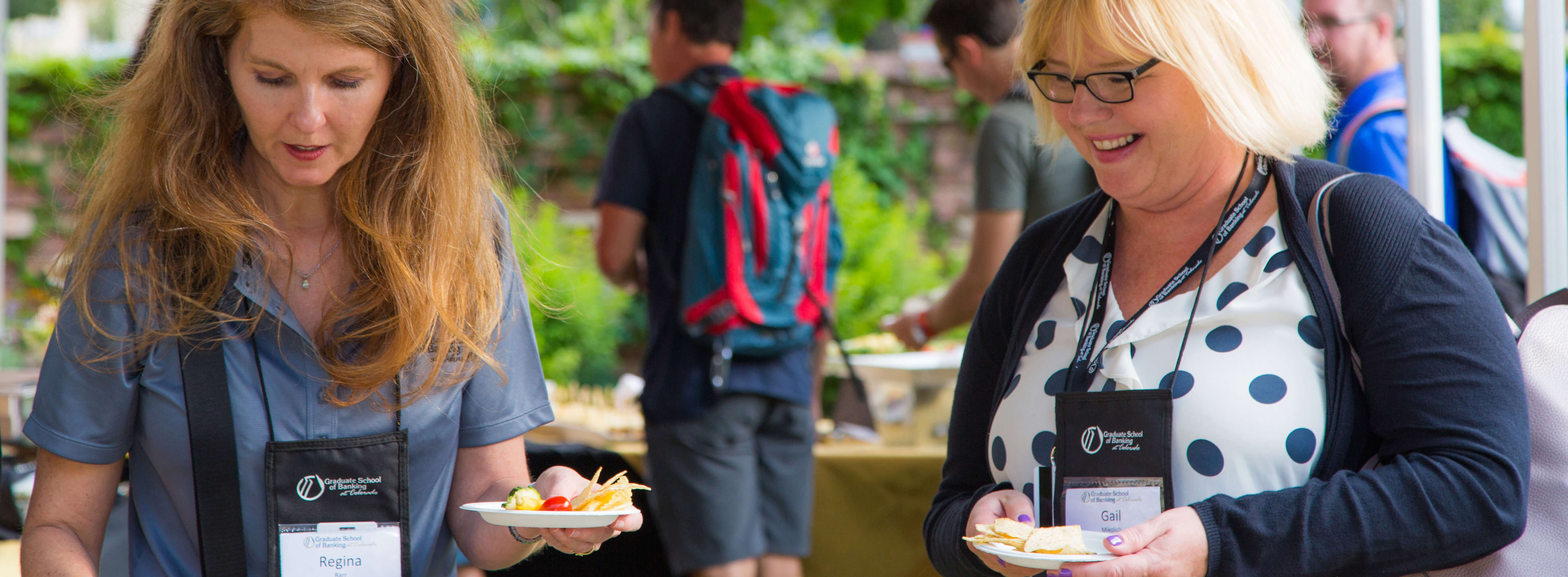 Female conference attendees talking and smiling while getting snacks from the catering table