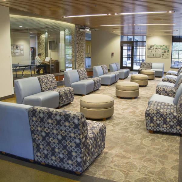 Williams Village North Hall lounge showing chairs, ottomans, carpet and tile flooring, windows