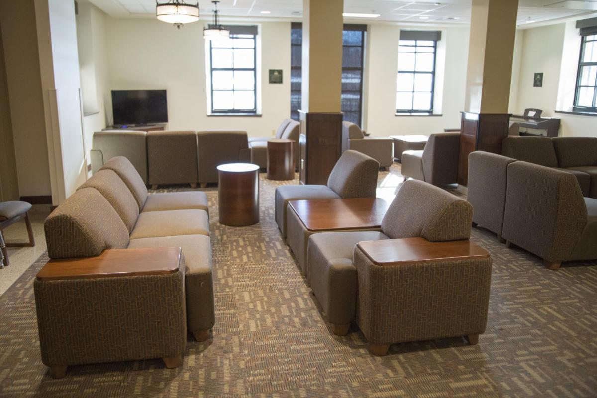 Baker lounge area with modular furniture, round side tables, carpeted floors, windows, tv