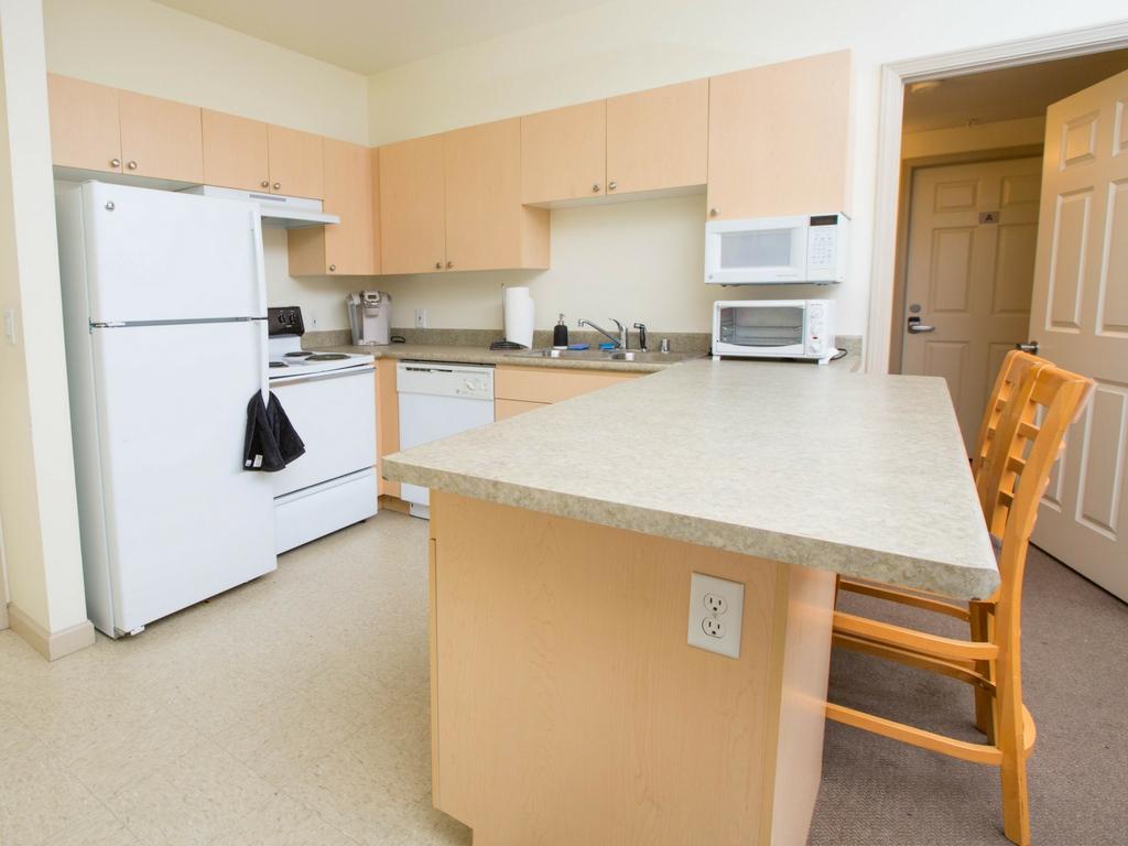 Kitchen with fridge, stove/oven, sink, microwave, breakfast bar with two stools