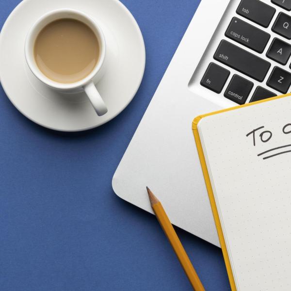 A laptop, pad, pencil, cup of coffee