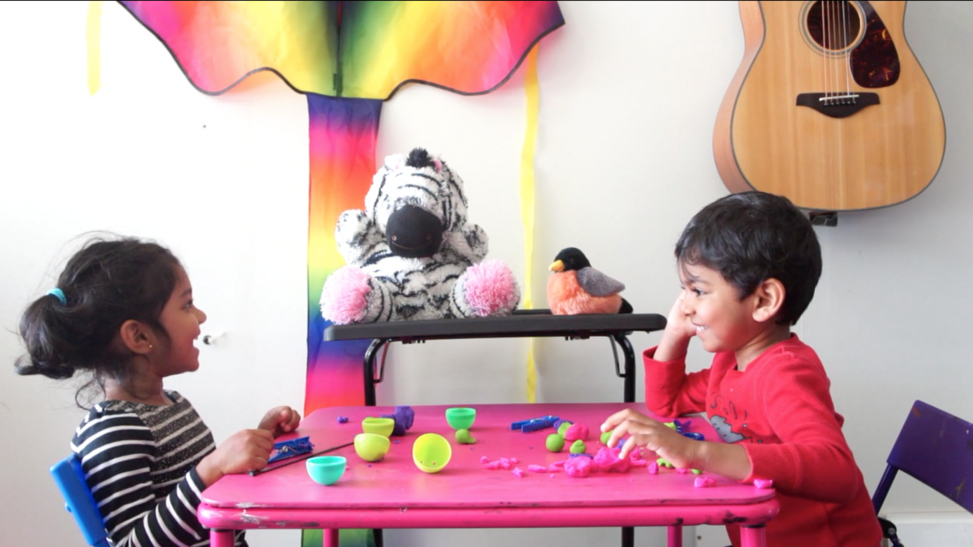 Two children interact with a MindScribe zebra stuffed toy. 