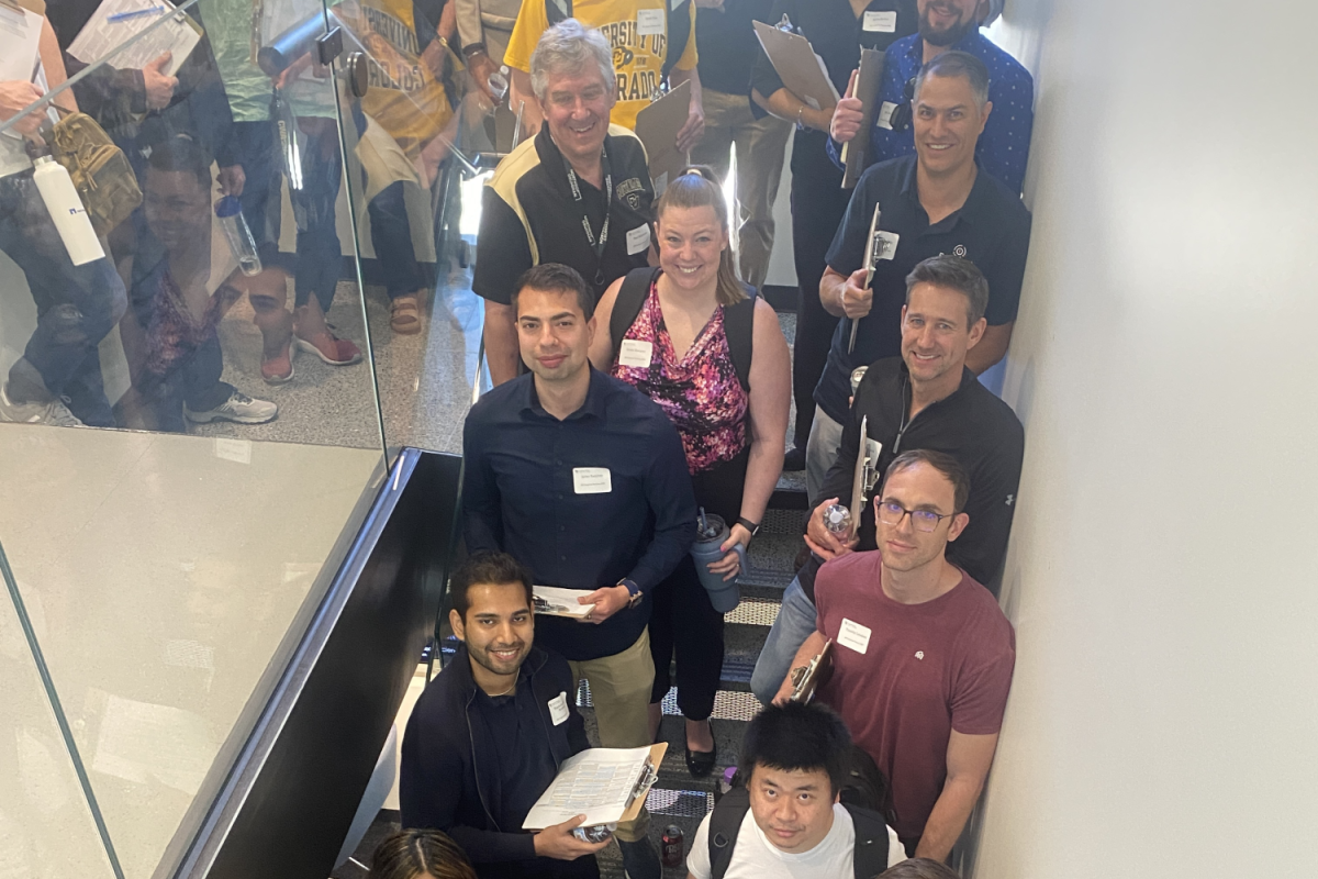 Computer science alumni in a stairwell with clipboards