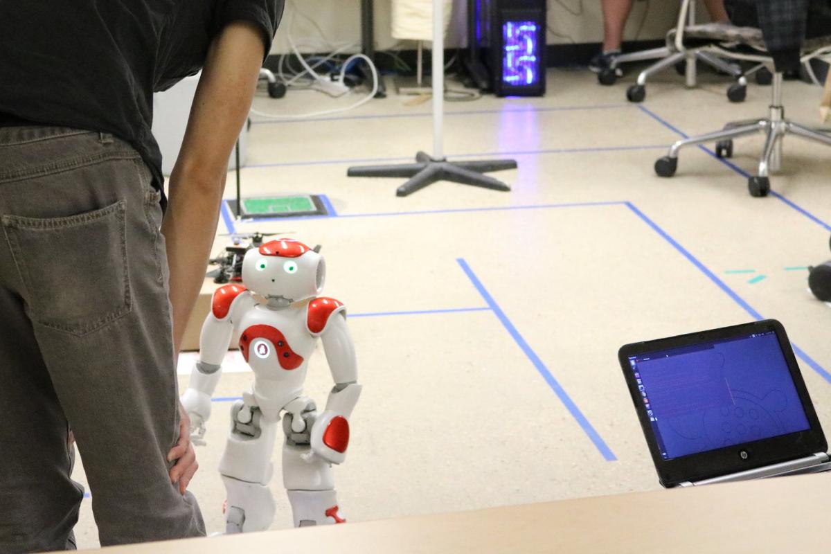 Graduate student interacting with artificially intelligent robot