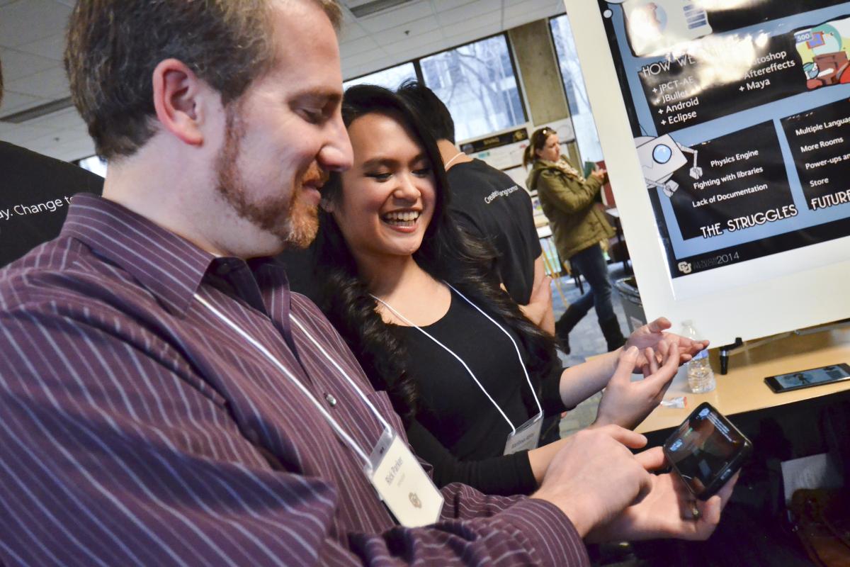 A student demonstrates her project to a visitor at the CS Expo.