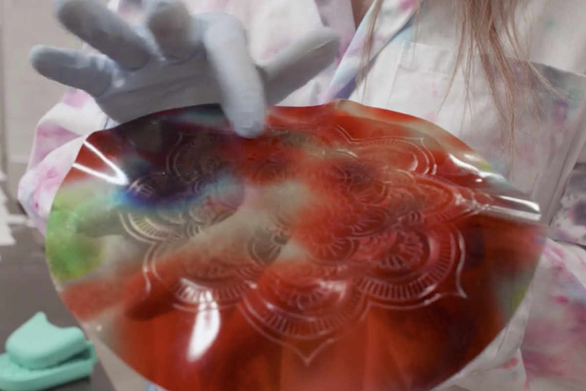 Gloved hands hold gelatin imprinted with patterns