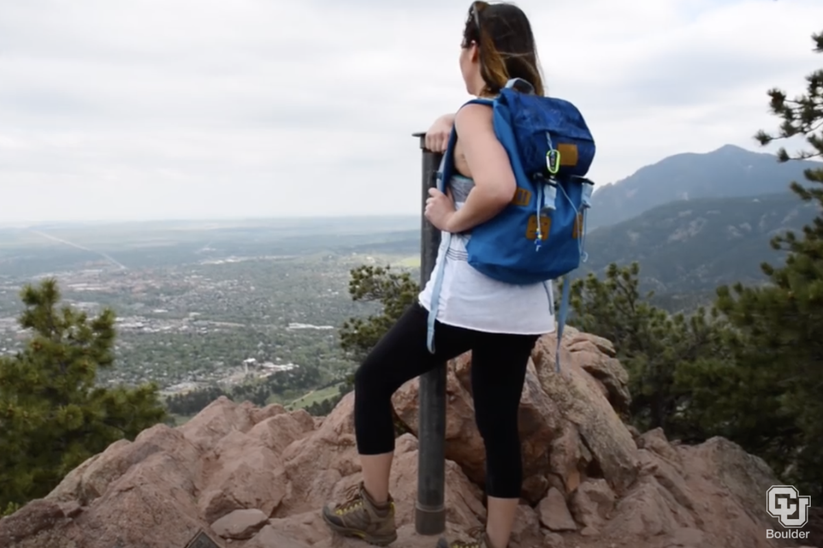 Hiker looks out on the city of Boulder from rock ledge