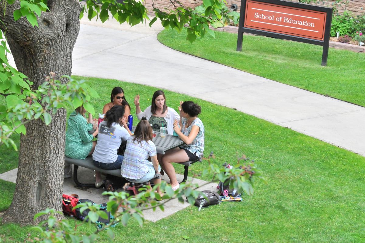 Students study outside at a picnic table.