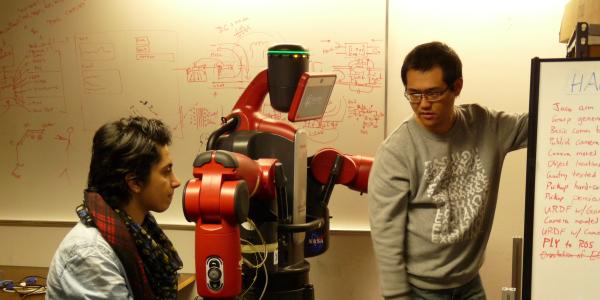 Two students discuss a robotics project in a lab