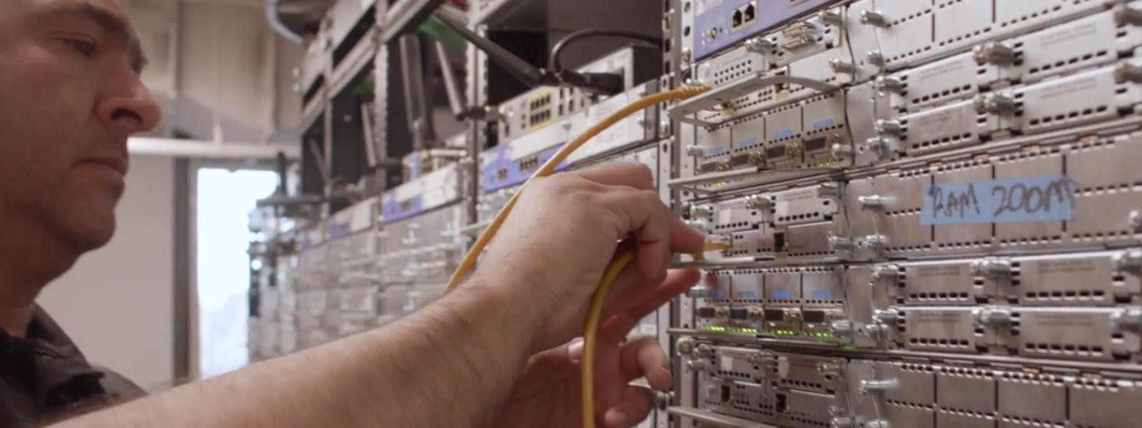 man plugging cords into network wall