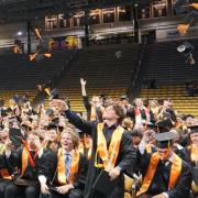 Students toss their mortar boards in the air at the end of a graduation ceremony in the CU Events Center